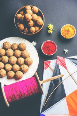 mutlu Makar Sankranti tebrik kartı - Tilgul veya bir kase veya plate haldi Recep ile ve Fikri Reel/Chakri /Spool renkli iplik veya manjha ve düz arka plan üzerinde uçurtma ile çiçeklerle gidecektir Til