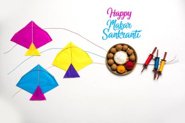 mutlu Makar Sankranti tebrik kartı - Tilgul veya bir kase veya plate haldi Recep ile ve Fikri Reel/Chakri /Spool renkli iplik veya manjha ve düz arka plan üzerinde uçurtma ile çiçeklerle gidecektir Til