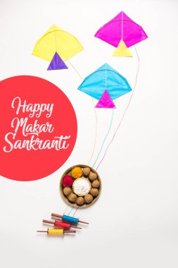 mutlu Makar Sankranti tebrik kartı - Tilgul veya bir kase veya plate haldi Recep ile ve Fikri Reel/Chakri /Spool renkli iplik veya manjha ve düz arka plan üzerinde uçurtma ile çiçeklerle gidecektir Til