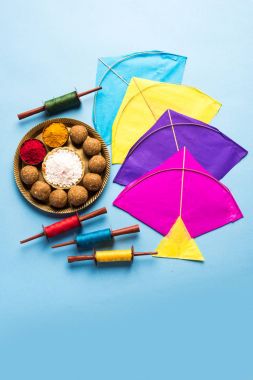 mutlu Makar Sankranti tebrik kartı - Tilgul veya bir kase veya plate haldi Recep ile ve Fikri Reel/Chakri /Spool renkli iplik veya manjha ve düz arka plan üzerinde uçurtma ile çiçeklerle gidecektir Til