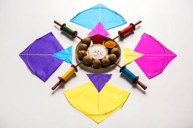 mutlu Makar Sankranti tebrik kartı - Tilgul veya bir kase veya plate haldi Recep ile ve Fikri Reel/Chakri /Spool renkli iplik veya manjha ve düz arka plan üzerinde uçurtma ile çiçeklerle gidecektir Til