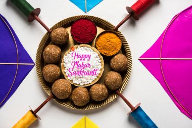 mutlu Makar Sankranti tebrik kartı - Tilgul veya bir kase veya plate haldi Recep ile ve Fikri Reel/Chakri /Spool renkli iplik veya manjha ve düz arka plan üzerinde uçurtma ile çiçeklerle gidecektir Til