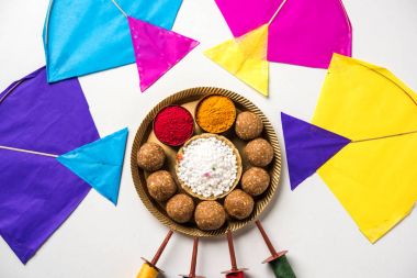 mutlu Makar Sankranti tebrik kartı - Tilgul veya bir kase veya plate haldi Recep ile ve Fikri Reel/Chakri /Spool renkli iplik veya manjha ve düz arka plan üzerinde uçurtma ile çiçeklerle gidecektir Til