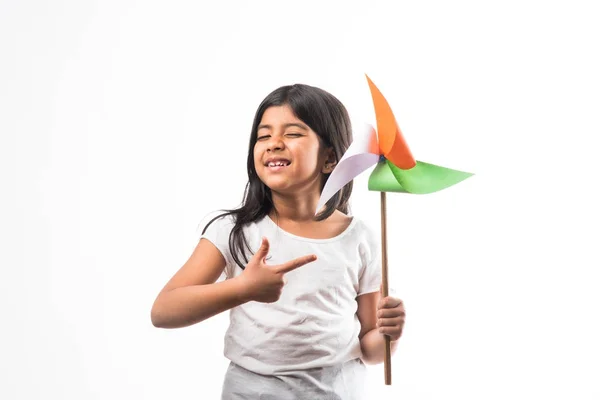 印度女孩与纸风车玩具由三或印第安旗子颜色组成 看着相机或与红心玩具 庆祝1月26日共和国日或8月15日独立日 — 图库照片