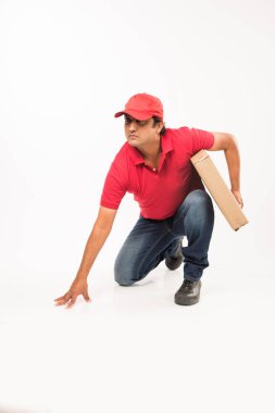 Teslimat kavramı - kırmızı ya da yeşil üniformalı yürüyüş veya atlama veya denetimi veya karton kutu ile kopya alanı sunan mutlu Hint veya teslim erkeklere portresi