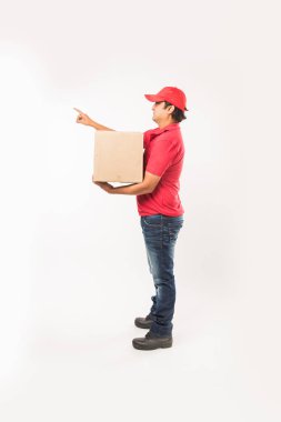 Teslimat kavramı - kırmızı ya da yeşil üniformalı yürüyüş veya atlama veya denetimi veya karton kutu ile kopya alanı sunan mutlu Hint veya teslim erkeklere portresi