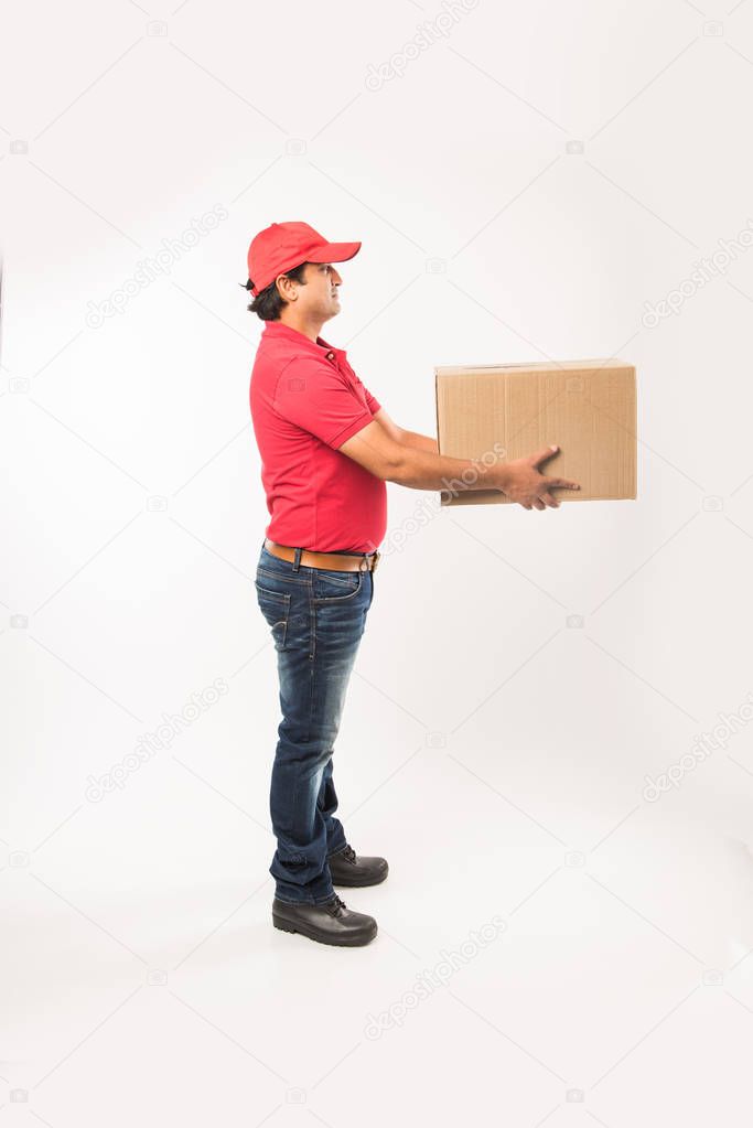 Delivery Concept - Portrait of Happy Indian or delivery man in red or green uniform walking or jumping or checking or presenting cardboard box with copy space