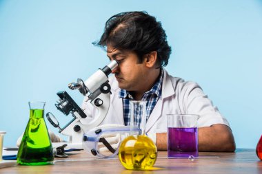 Asya/Hindistan erkek bilim adamı veya doktor ya da bilim öğrenci mikroskop ve kimyasallar, dizüstü bilgisayar ve smartphone bir laboratuvarda deneme