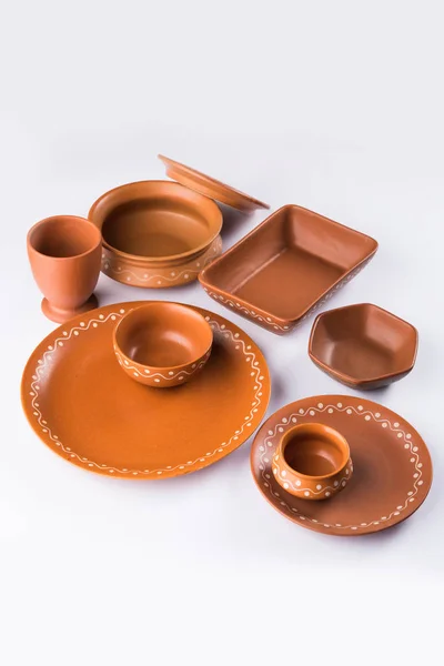 Empty terracotta dinnerware or dining set like plate, soup bowl, serving bowl, glass made up of brown clay, isolated over white