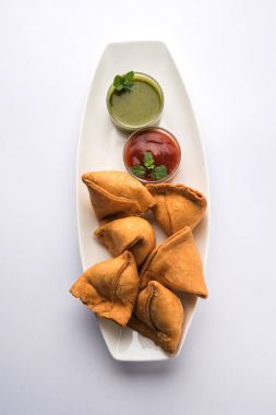Sebze Samosa bir üçgen şekli pakora Aloo sabji, yeşil Hint turşusu ve domates sosu ile servis ile doldurulmuş olduğunu. seçici odak