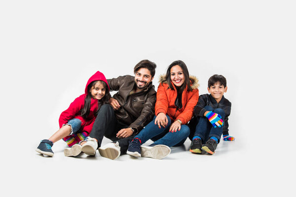 Индийская семья в теплой одежде сидит на белом фоне. Готов к зимней концепции