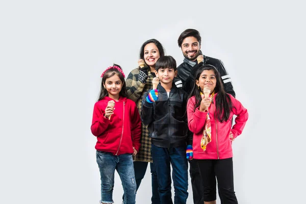 Indian family eating ice cream in warm clothes on white background