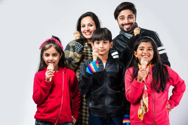 Indian family eating ice cream in warm clothes on white background