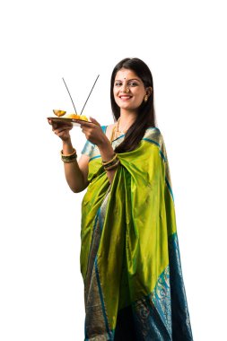 Pooja Thali 'yi tutan sari giymiş Hintli genç bir kadın beyaz arka planda izole bir şekilde Diwali ya da Hindu festivalini kutluyor. seçici odak