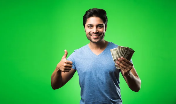 Indian happy man holding money, standing isolated against green chroma screen