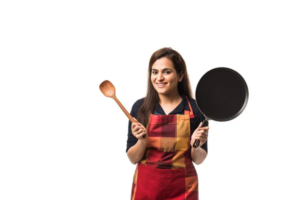 Indian / asian woman chef wearing Apron and holding Pan and spatula while standing isolated over white background