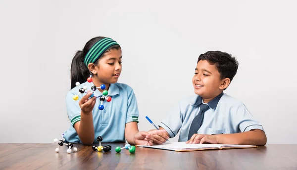 Indian school boy and girl or science student in uniform Using Molecular Model Kit for studying physics, selective focus