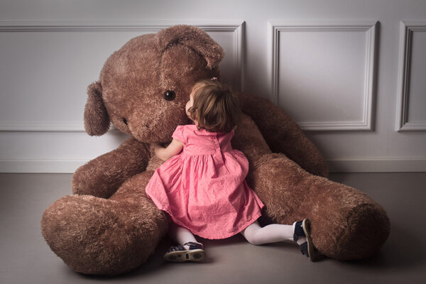 Little girl hugging a big teddy bear