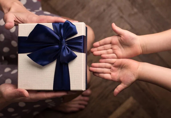 Madre dando una gran caja de regalo a su hijo con la mano abierta — Foto de Stock