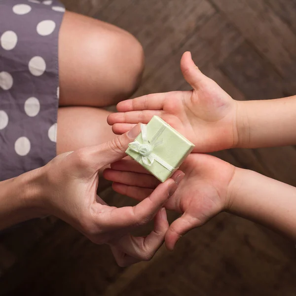 Mãe dando um pequeno presente para seu filho com a mão aberta — Fotografia de Stock