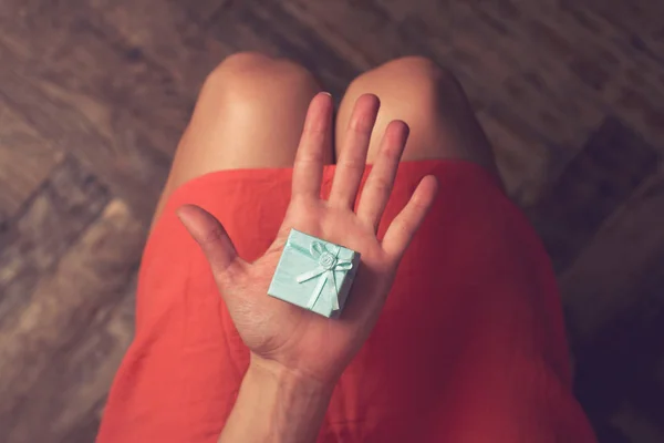 Vrouw met een kartonnen kleine blauwe geschenkdoos met lint — Stockfoto