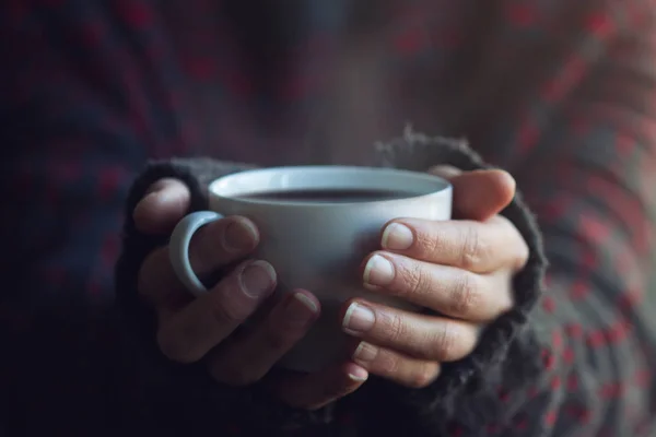 Kvinna i tröja händer som håller en kopp varmt kaffe — Stockfoto