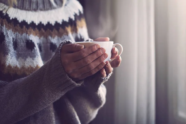 Woman in knitted sweater hands holding a cup of warm coffee — Stock Photo, Image