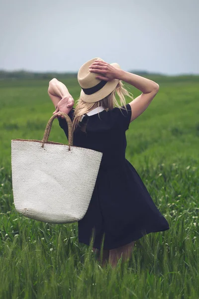 Mulher com vestido preto em um campo de trigo verde — Fotografia de Stock