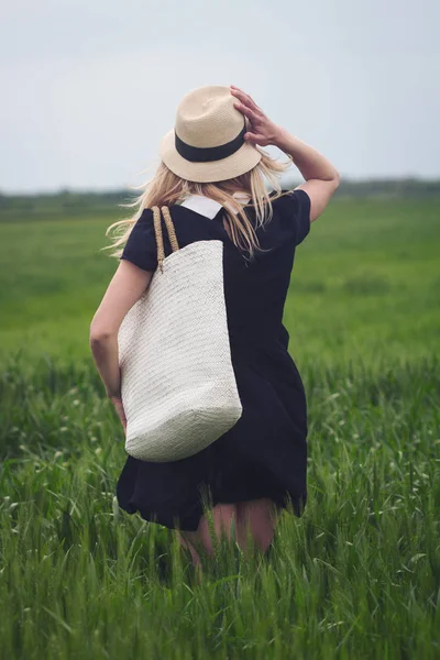 Mulher com vestido preto em um campo de trigo verde — Fotografia de Stock