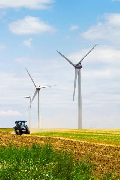 Eolian wind turbine with plough tractor in the background — Stock Photo, Image