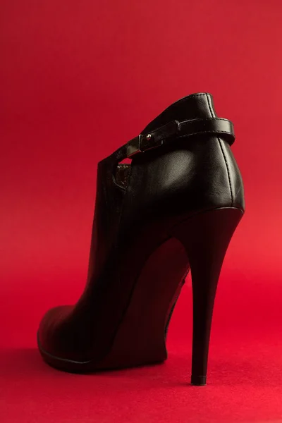 Högklackade svarta skor på röd bakgrund — Stockfoto