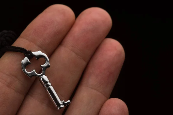 Mano sosteniendo una pequeña llave de plata — Foto de Stock