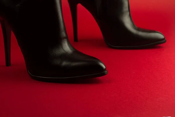 Högklackade svarta skor på röd bakgrund — Stockfoto