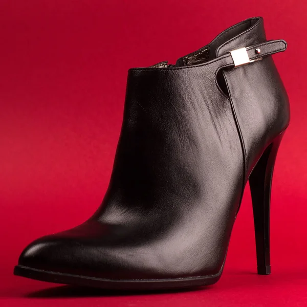 Černý vysoký podpatek boty na červeném pozadí — Stock fotografie