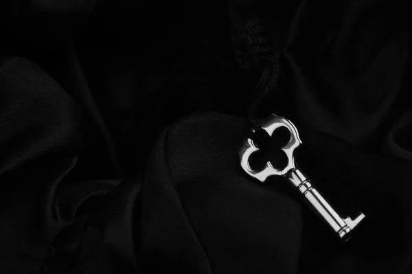 Маленький серебряный ключ на темном шелковом фоне — стоковое фото