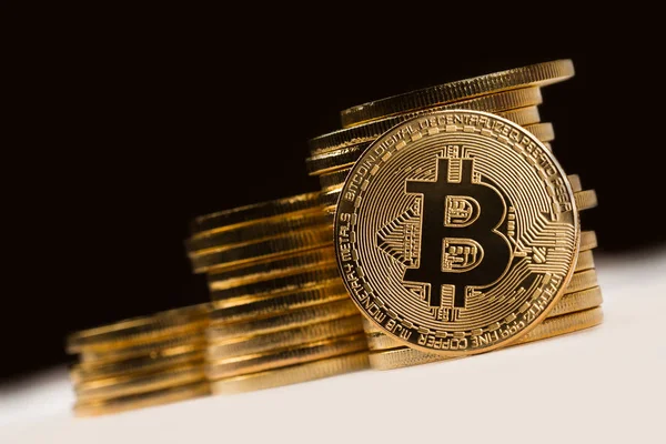 Golden bitcoin in front of a pile of golden metallic coins on bl — Stock Photo, Image