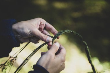 Çiçeklerle çim çelengi ören genç bir kadın