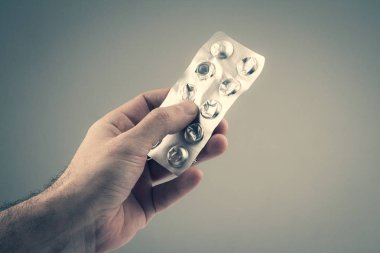 closeup of Caucasian male hand holding pills packaging foil