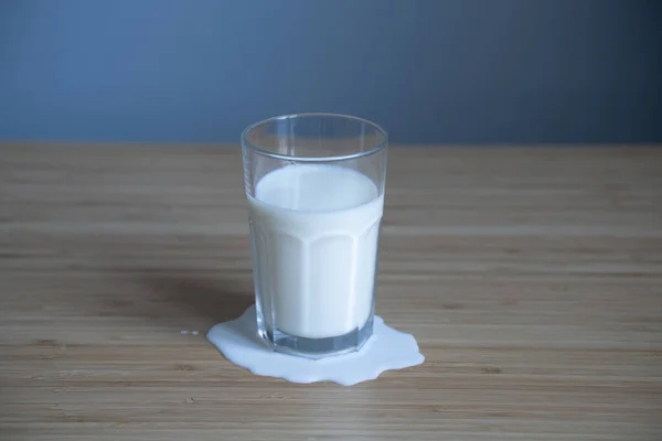 Främre Närbild Glas Pöl Spilld Mjölk Ljusa Trä Bord Naturlig — Stockfoto