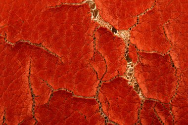 Aşırı kahverengi çatlamış yapay deri arka plan dokusu ve altında sünger olan makro yakın çekim detayı.