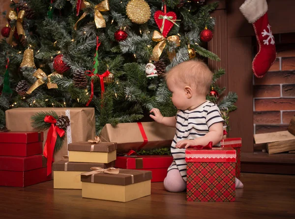 Hediyeler Noel ağacı önünde ile katta oturan neşeli bebek kız