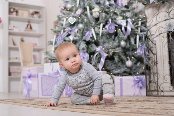 Fröhliches kleines Mädchen sitzt auf dem Boden vor dem Weihnachtsbaum — Stockfoto