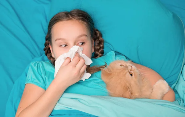 A criança está fria na cama com um lenço e gato — Fotografia de Stock