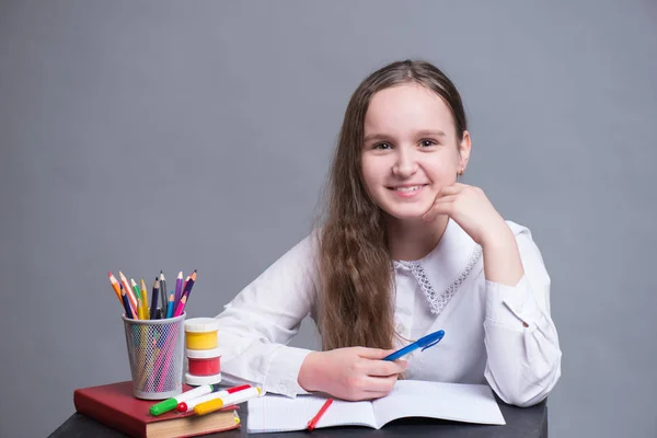 Школьница сидит за своим столом и делает домашнее задание — стоковое фото