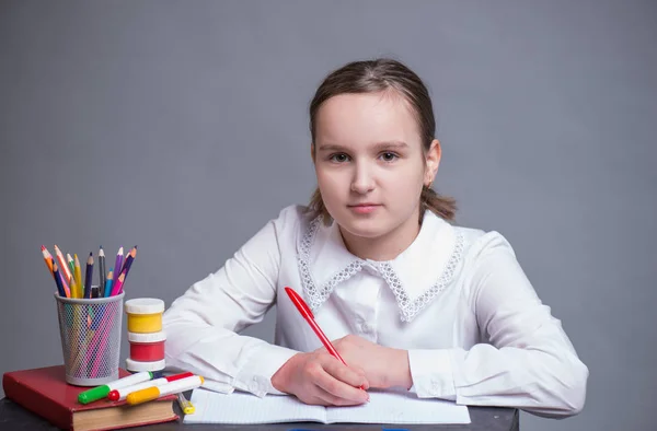Счастливая школьница сидит за столом — стоковое фото