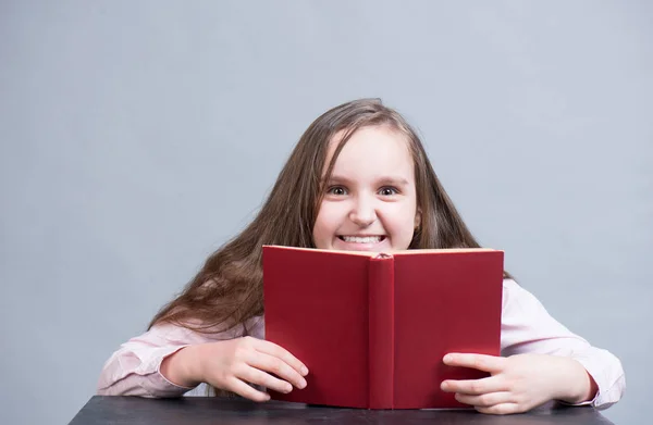 Estudante encantadora segurando um livro vermelho em suas mãos — Fotografia de Stock
