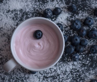 Karanlık bir arka plan üzerinde yaban mersini ile yoğurt