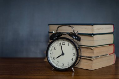 Kitap ve bir çalar saat bir okul yönetimi arka plan üzerinde yalan