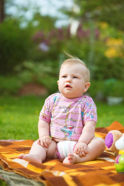 Mollig, niedliches Baby auf dem Gras sitzend — Stockfoto