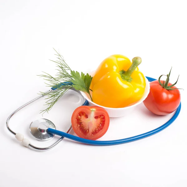 Steteskop ve sebze beyaz bir arka planda bir sağlıklı beslenme kavramı — Stok fotoğraf